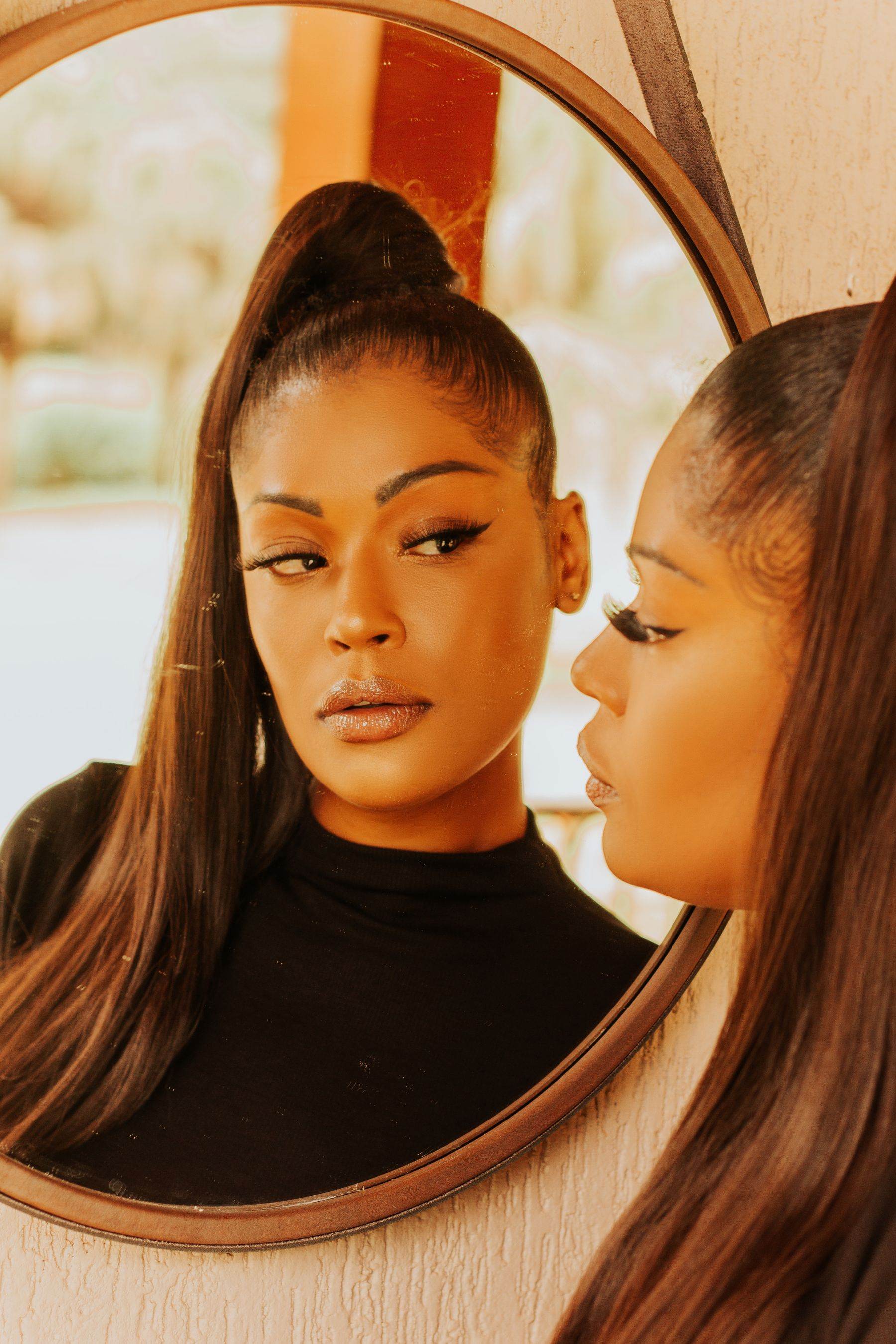 A sleek high ponytail reflected in a round mirror, in warm afternoon light